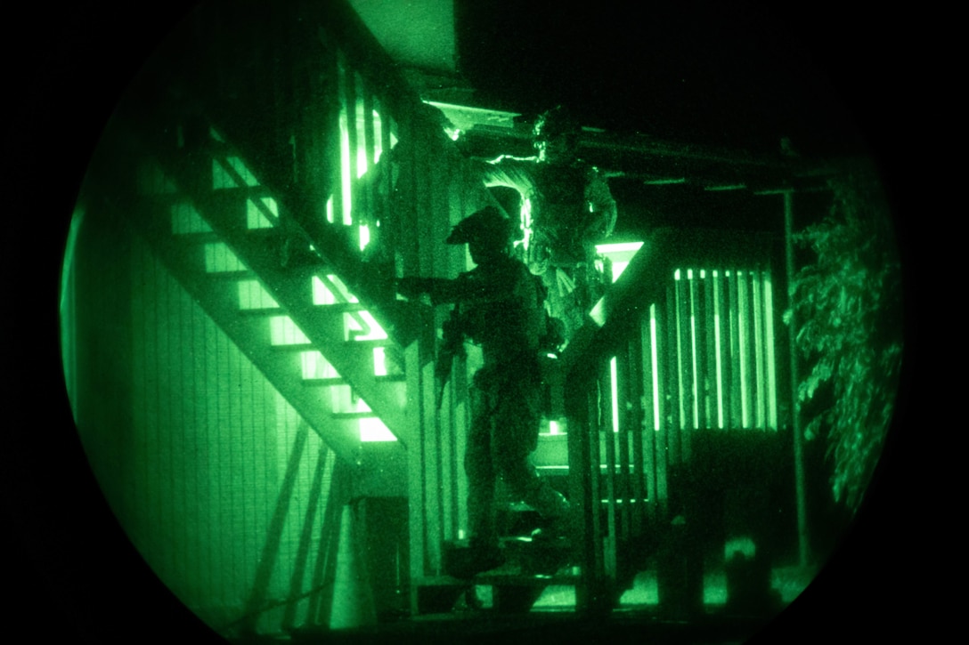 Marines walk down a stairway inside a building at night.