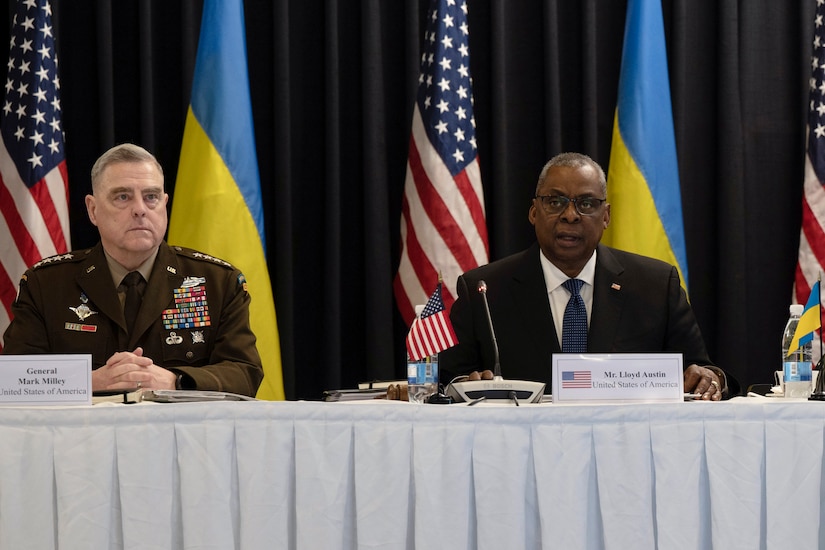 Secretary of Defense Lloyd J. Austin III and Army Gen. Mark A. Milley sit at table in front of U.S., Ukraine flags.