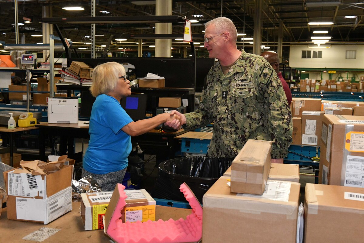 Photo shows woman and man shaking hands next to boxes