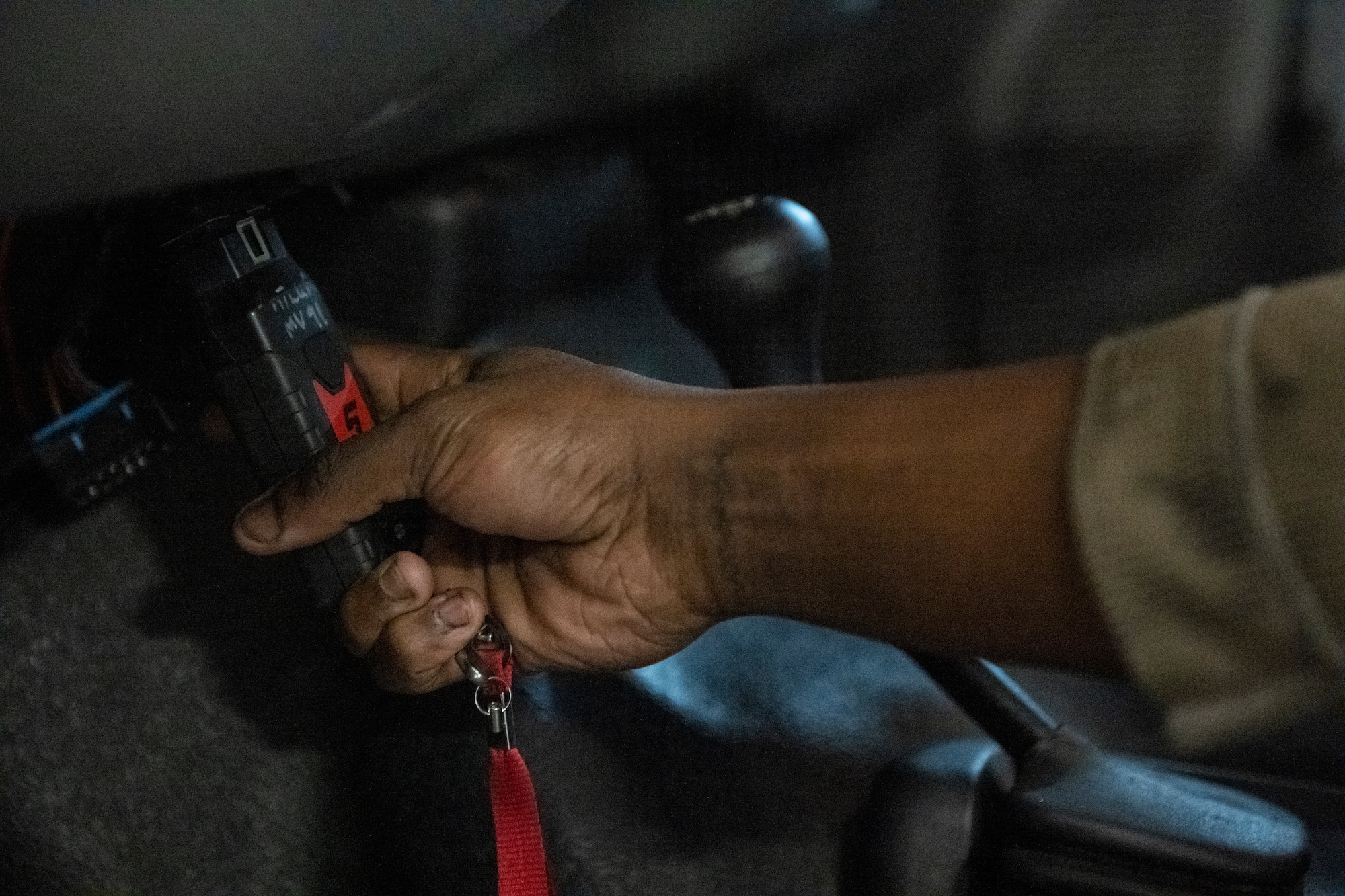 A photo of a hand holding a scanning puck device, plugging it into a port under the steering wheel in a truck.