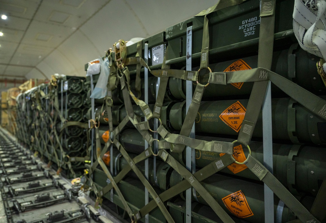 A row of pallets bearing the word “explosive” sit in a small enclosure.