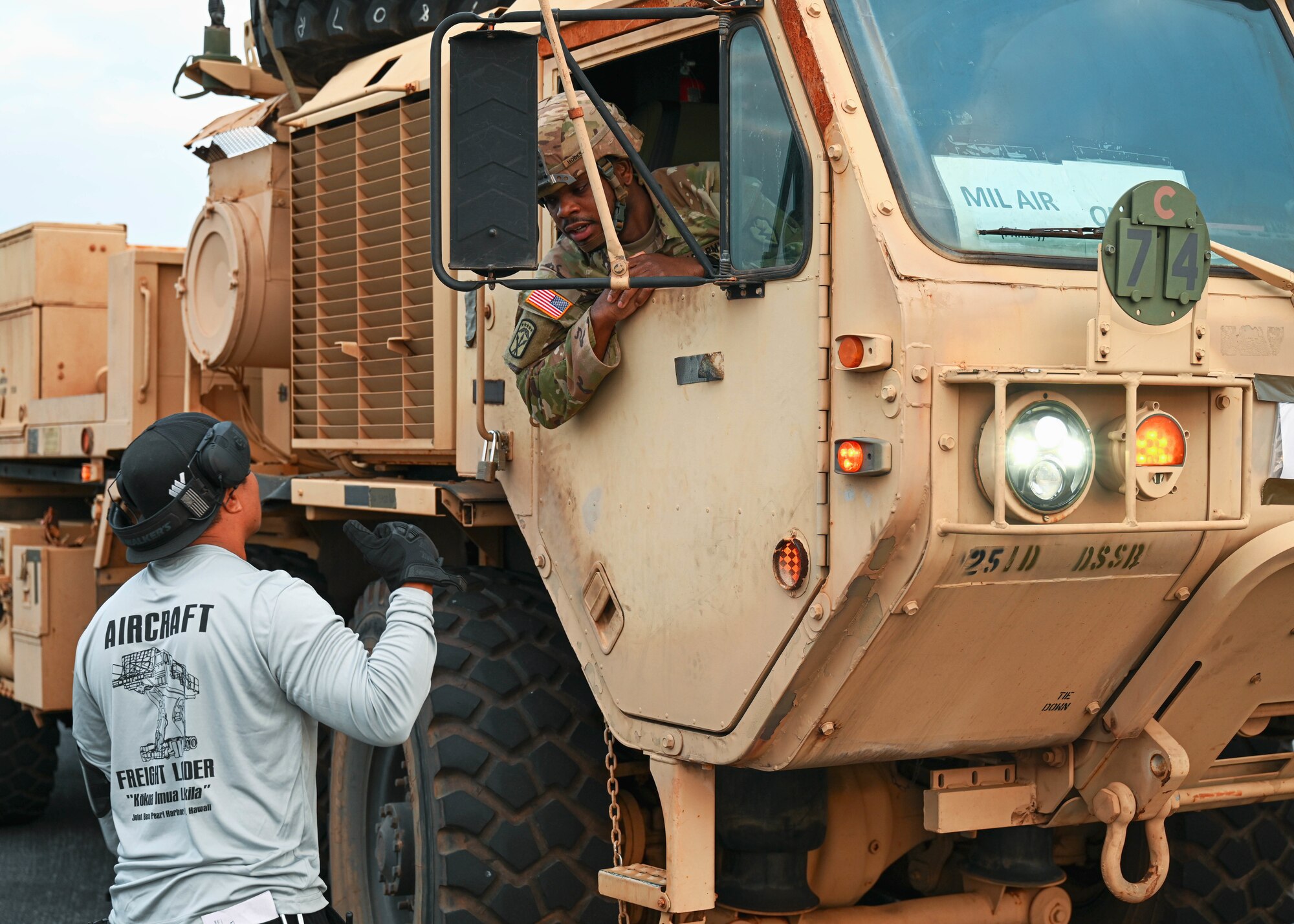 A Soldier assigned to the 593d Expeditionary Sustainment Command, 25th Division Sustainment Brigade, 25th Infantry Division, coordinates with an aircraft freight loader at Joint Base Pearl Harbor-Hickam, Hawaii, Jan. 10, 2022. Equipment was transported to the Island of Hawaii for a gunnery sustainment exercise that will allow Soldiers to qualify on several weapon systems. (U.S. Air Force photo by Senior Airman Zoie Cox)