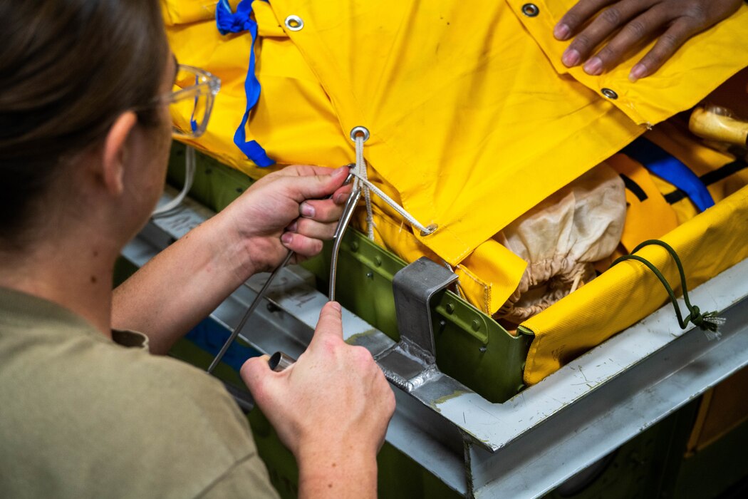 Senior Airman Karlie Kohmetscher, 15th Operations Support Squadron aircrew flight equipment journeyman, packs a 46-man life raft at Joint Base Pearl Harbor-Hickam, Hawaii, Jan. 11, 2023. The life rafts on a C-17 Globemaster III are checked periodically to ensure they inflate safely if needed in an in-flight emergency. (U.S. Air Force photo by Senior Airman Makensie Cooper)