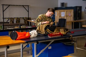 Senior Airman Karlie Kometscher, 15th Operations Support Squadron aircrew flight equipment journeyman, works on a Butler Parachute BA-30 low profile parachute system at Joint Base Pearl Harbor-Hickam, Hawaii, Jan. 11, 2023. AFE specialists ensure aircrew have the necessary supplies for in-flight emergency use, providing safety to the crew and passengers. (U.S. Air Force photo by Senior Airman Makensie Cooper)