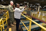 Photo shows man and woman looking out over warehouse floor