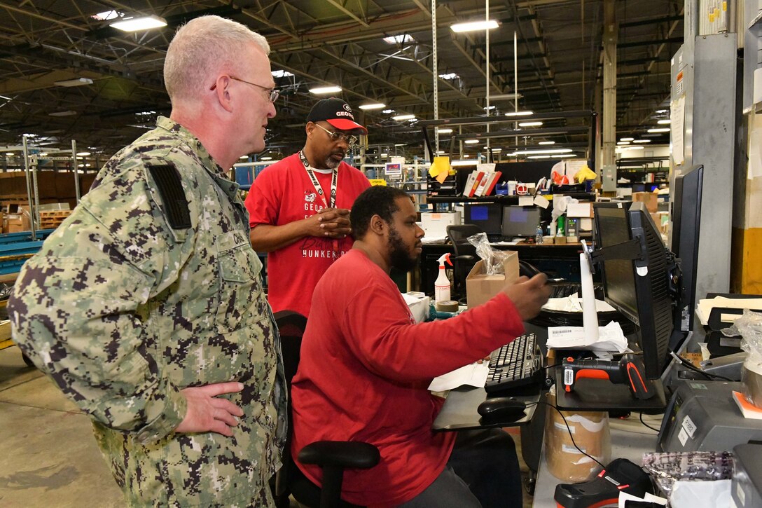 Photo shows three men looking at a computer