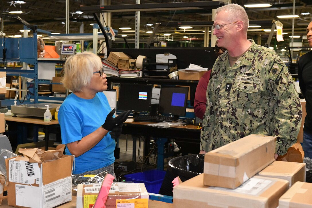 Photo shows woman speaking to man next to boxes