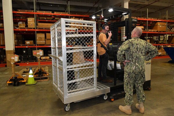 Photo shows man on forklift speaking to man standing on floor