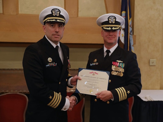 Capt. Jason Pittman, commodore, Submarine Squadron Six, right, presents the Legion of Merit award to Capt. Bennett Christman, left, during a change of command ceremony for the Virginia-class fast-attack submarine USS New Hampshire (SSN 778) onboard Naval Support Activity Hampton Roads, Jan. 20.