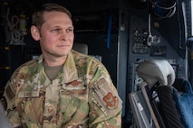 Man in Air Force uniform sits inside of the cockpit of a Combat Talon with mechanical elements visible in the background.