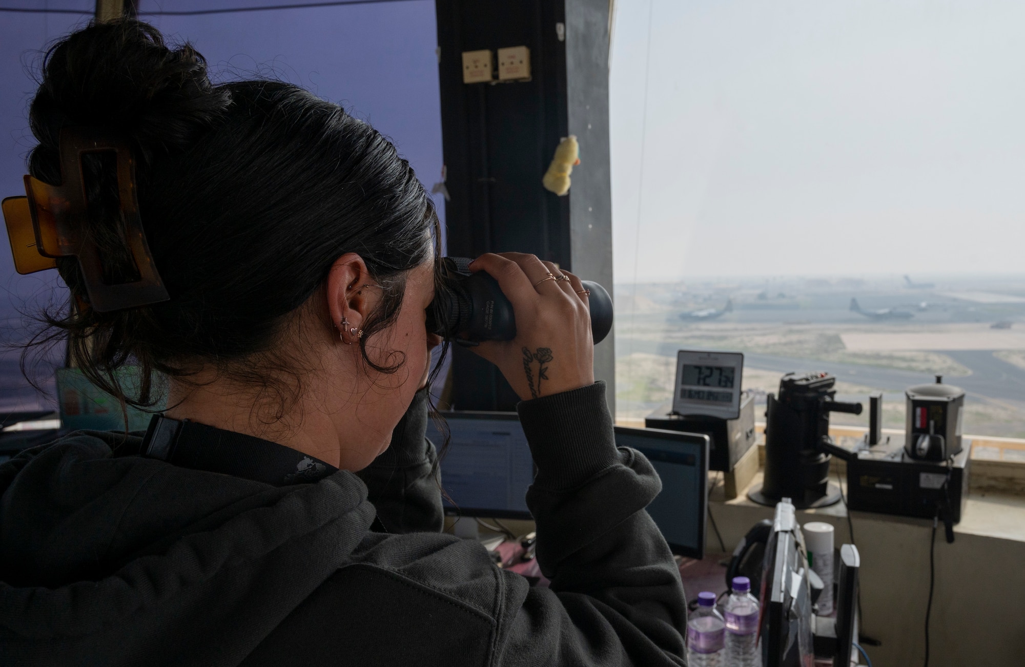 Ms. Allison Neilsen, an Air Traffic Training Manager with the 407th Expeditionary Operations Support Squadron, looks through a pair of binoculars in the Air Traffic Control Tower at Ali Al Salem Air Base, Jan. 16, 2023.