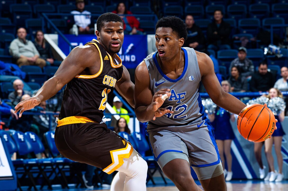 A basketball player dribbles the ball past an opposing player as he makes his way to the basket.