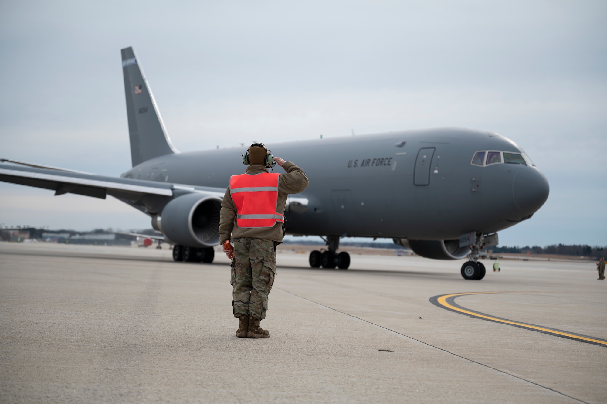 Senior Airman Reid Carter, a crew chief with the 64th Air Refueling Squadron, marshals a KC-46 Pegasus Jan. 19, 2023 at Pease Air National Guard Base, New Hampshire. The mission was the first flight fully generated by all 64th ARS air and ground crews. (U.S. Air National Guard photo by Staff Sgt. Victoria Nelson)
