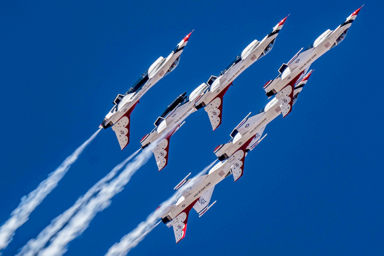 Aircraft fly in formation as jet streams trail behind.