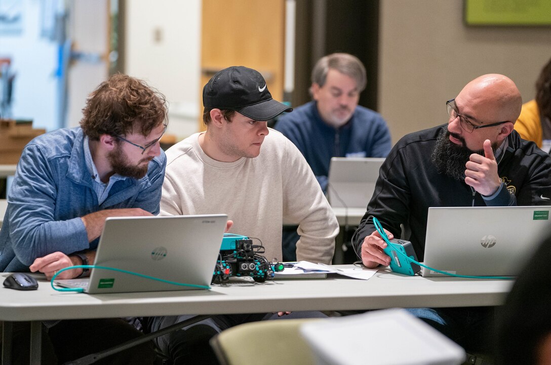 IMAGE: Integrated Combat Systems Department scientist Justin Lowell (center) mentors Westmoreland High School teacher Chastaine Perry (left) and Colonial Beach High School Supervisor of Technology Ameer Mir in preparing their schools’ robots for this year’s Innovation Challenge @ Dahlgren. The robotics competition takes place March 31-April 1 at the University of Mary Washington Dahlgren Campus.