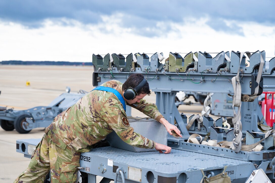 Airman secures straps on missile rack.