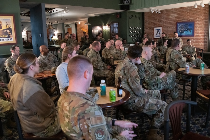 A crowd of military members sit in a room.