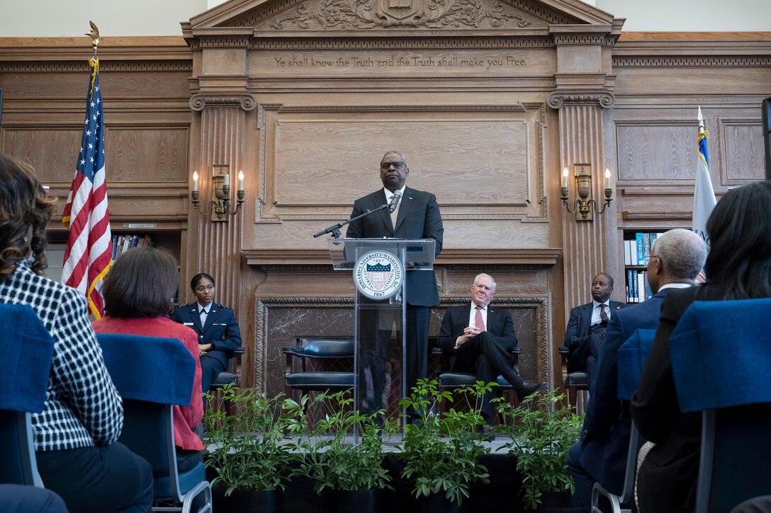 Secretary of Defense Lloyd J. Austin III speaks at a lectern to a seated audience.