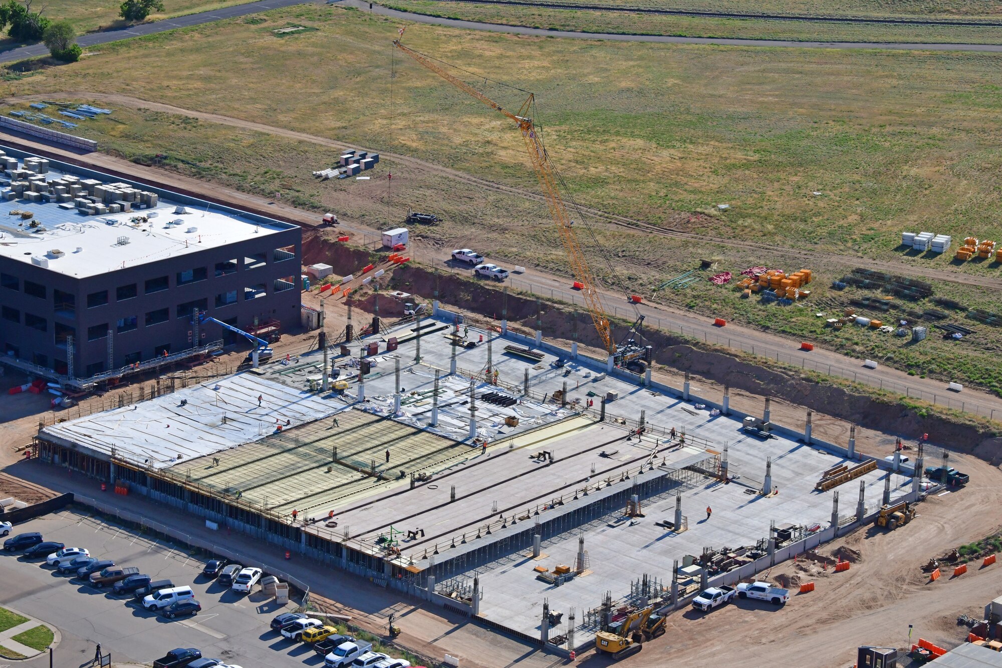 The parking structure is being constructed to provide parking for the workers that will be working in the Sentinel Ground Based Strategic Deterrent Mission Integration Facility, which is being constructed adjacent to the parking garage. Companies RLW and Hensel Phelps were contracted to form and place all structural concrete, reinforcing, and post-tensioning. There are 74,000 square feed of slab-on-grade and three elevated parking levels with more than 216,000 square feet of parking space, enough room for 850 cars. The garage will have three stair towers and an elevator shaft on the north end. The project has been going since September 2021 and is expected to finish in February 2023.