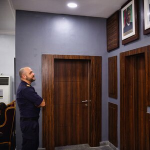 Italian Navy Secondo Capo Scelto q.s. Daniele De Sanctis, Virtual Regional Maritime Traffic Centre expert, looks at a portrait of Nigeria's president in the Naval Dockyard in Lagos, Nigeria, Jan. 23, 2023. Obangame Express 2023, conducted by U.S. Naval Forces Africa, is a maritime exercise designed to improve cooperation, and increase maritime safety and security among participating nations in the Gulf of Guinea and Southern Atlantic Ocean. U.S. Sixth Fleet, headquartered in Naples, Italy, conducts the full spectrum of joint and naval operations, often in concert with allied and interagency partners, in order to advance U.S. national interests and security and stability in Europe and Africa. (U.S. Navy photo by Mass Communication Specialist 1st class Cameron C. Edy)