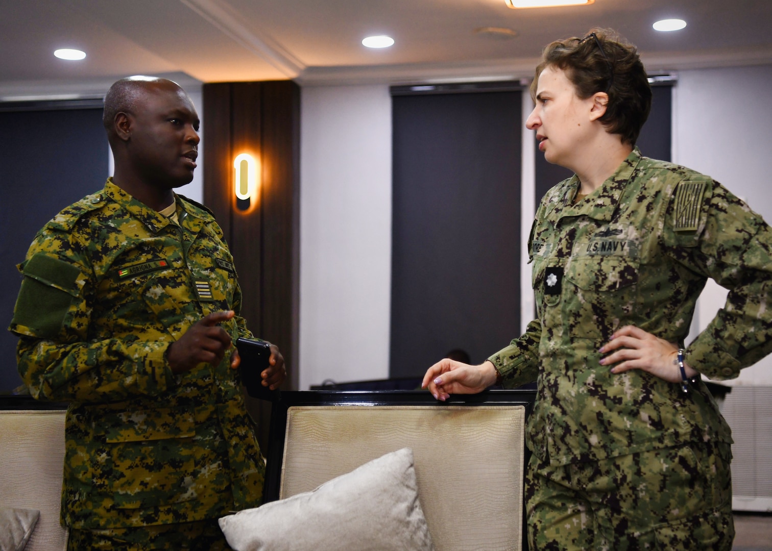 Togo Navy Cmdr. Sama Agrigna, a liaison officer, speaks with Cmdr. Victoria Moore, a naval attache to the U.S. Consulate in Nigeria, in the Naval Dockyard in Lagos, Nigeria, Jan. 23, 2023. Obangame Express 2023, conducted by U.S. Naval Forces Africa, is a maritime exercise designed to improve cooperation, and increase maritime safety and security among participating nations in the Gulf of Guinea and Southern Atlantic Ocean. U.S. Sixth Fleet, headquartered in Naples, Italy, conducts the full spectrum of joint and naval operations, often in concert with allied and interagency partners, in order to advance U.S. national interests and security and stability in Europe and Africa. (U.S. Navy photo by Mass Communication Specialist 1st class Cameron C. Edy)