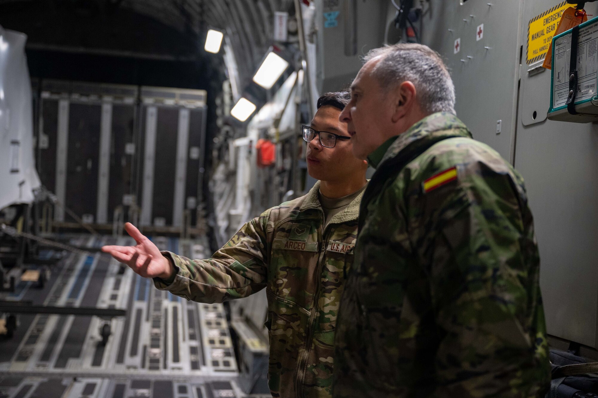 Senior Airman Frankie Arceo, 3rd Airlift Squadron loadmaster, speaks to a member of the Spanish army about cargo details before downloading a CH-47F Chinook helicopter from a C-17 Globemaster III assigned to Dover Air Force Base, Delaware, during a foreign military sales mission at Torrejón Air Base, Spain, Jan. 16, 2023. The United States and Spain recognize the central importance of the NATO alliance in ensuring transatlantic peace and security. As NATO allies for 40 years, the U.S. and Spain are steadfastly committed to providing NATO with ready forces and capabilities, strengthening transatlantic ties. (U.S. Air Force photo by Senior Airman Faith Barron)