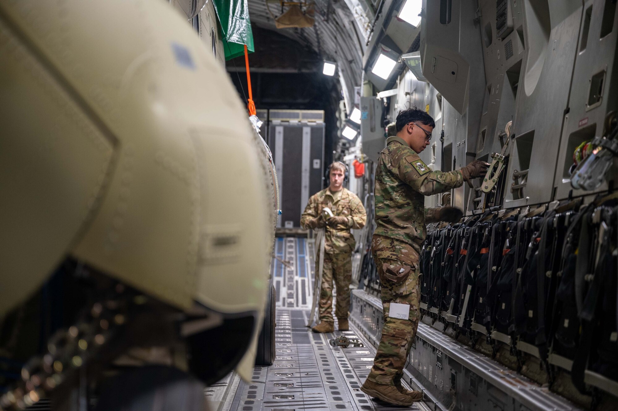 Senior Airman Frankie Arceo, 3rd Airlift Squadron loadmaster, prepares cargo chains before downloading a CH-47F Chinook helicopter from a C-17 Globemaster III assigned to Dover Air Force Base, Delaware, during a foreign military sales mission at Torrejón Air Base, Spain, Jan. 16, 2023. The United States and Spain are close allies and have excellent relations based on shared democratic values, including the promotion of democracy and human rights. (U.S. Air Force photo by Senior Airman Faith Barron)