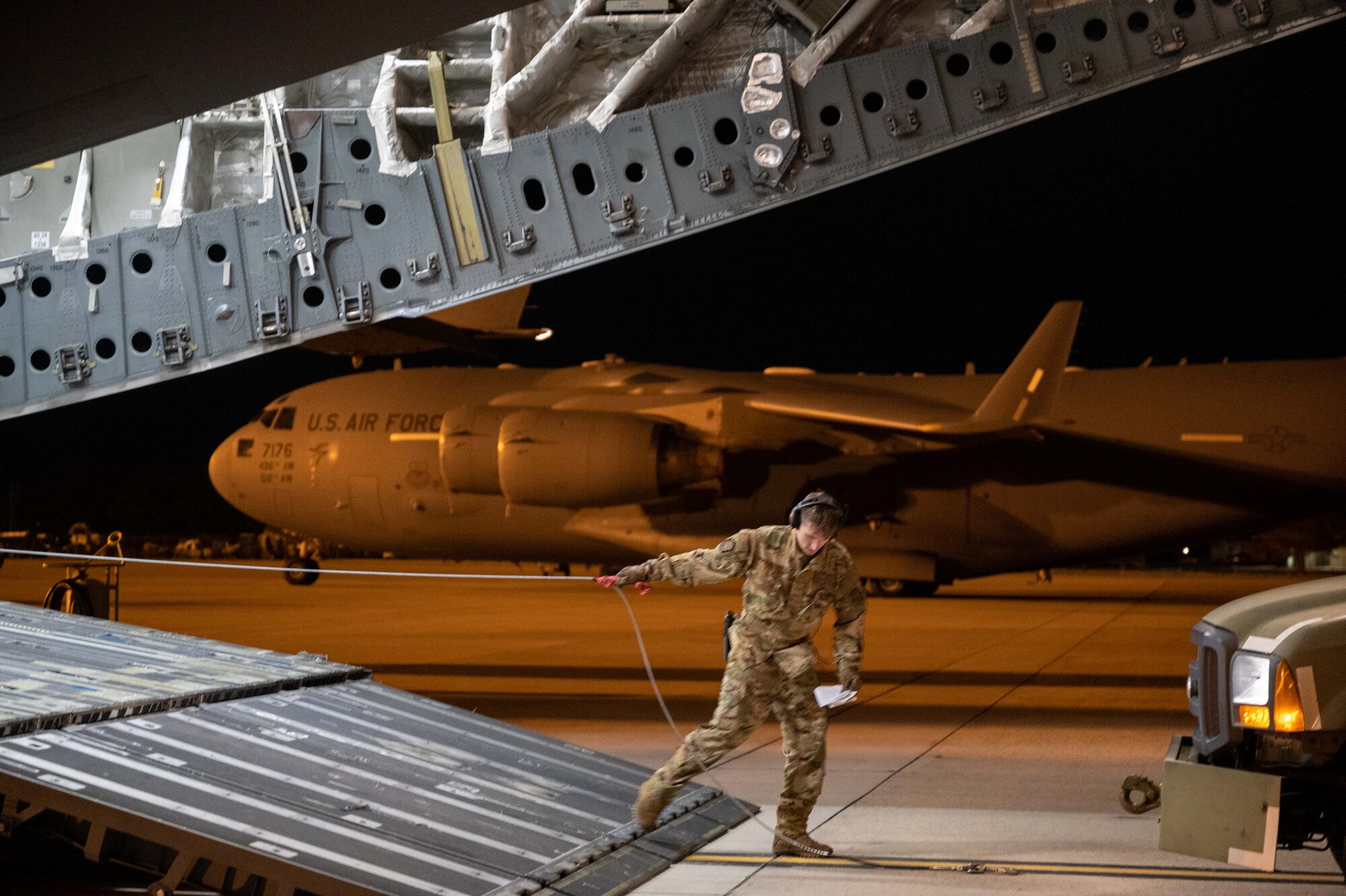 Senior Airman Matthew Warren, 3rd Airlift Squadron loadmaster, reels a winch of a C-17 Globemaster III during a foreign military sales mission at Dover Air Force Base, Delaware, Jan. 14, 2023. The C-17 transported a CH-47F Chinook helicopter to Torrejón Air Base, Spain, as part of the Department of Defense’s FMS program. (U.S. Air Force photo by Senior Airman Faith Barron)