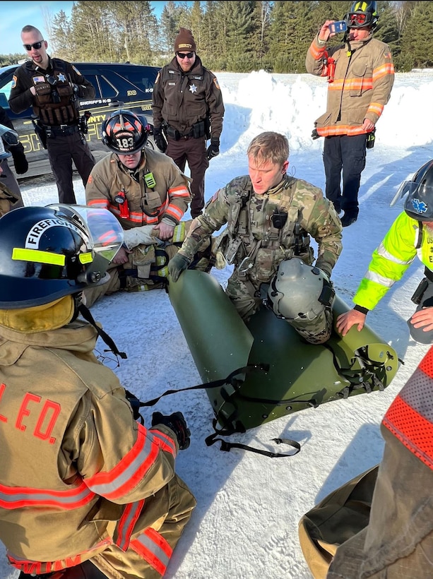 Sgt. Patrick Blaesing, a Wisconsin Army National Guard combat medic, works with local first responders to load a simulated patient for transport by Black Hawk helicopter during a search and rescue training exercise Jan. 14, 2023, in southern Lincoln County.