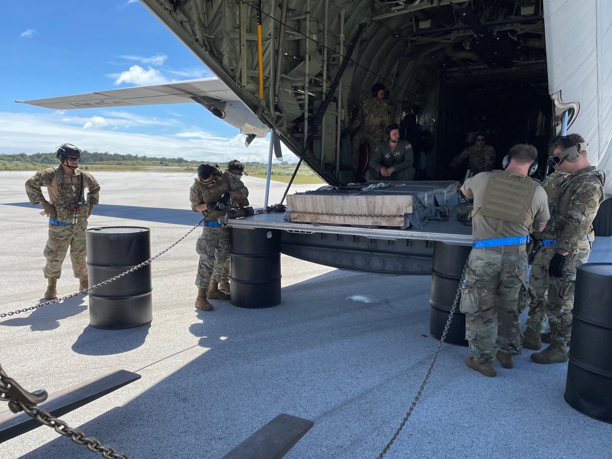 Six airmen offload cargo by hand from an airplane
