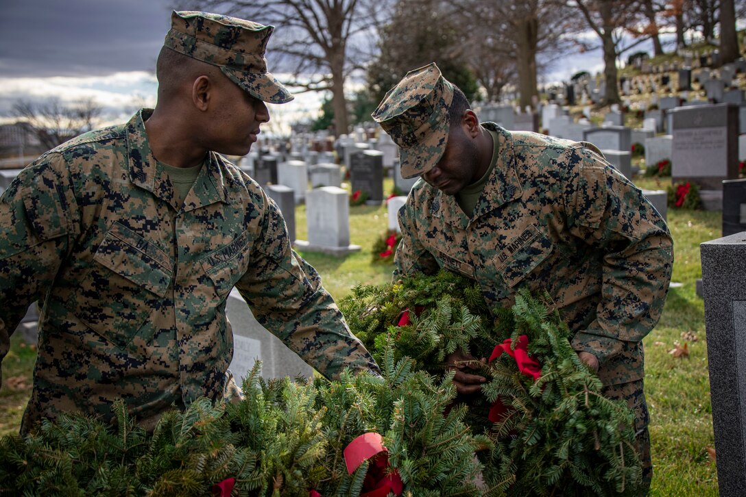 Sergeant Moussa Ba, water support technician, and Sgt. Timothy D. Bennet Jr., electrician, clear wreaths from gravesites at Arlington National Cemetery on Jan 20, 2023. Over the weekend, Marine Barracks Washington had the solemn honor of participating in clearing wreaths from over 250,000 gravesites in remembrance and honor of our nation’s fallen service members and their families. (U.S. Marine Corps photo by Cpl. Mark Morales)