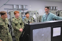 Daniel Weissgerber (far right), an electrical engineer at Naval Surface Warfare Center, Philadelphia Division (NSWCPD) discusses the Integrated Bridge Navigation System with U.S. Naval Academy students assigned to the Naval Architecture and Ocean Engineering (EN) 350 Marine Engineering Systems Class; (from left) Midshipman 2nd class Brandon McGuaghan, Midshipman 2nd class Ishmael Ian, and Midshipman 2nd class Liam Nawara. The Naval Academy students visited NSWCPD on Oct. 26, 2022 to gain on-site experience with different naval technologies.