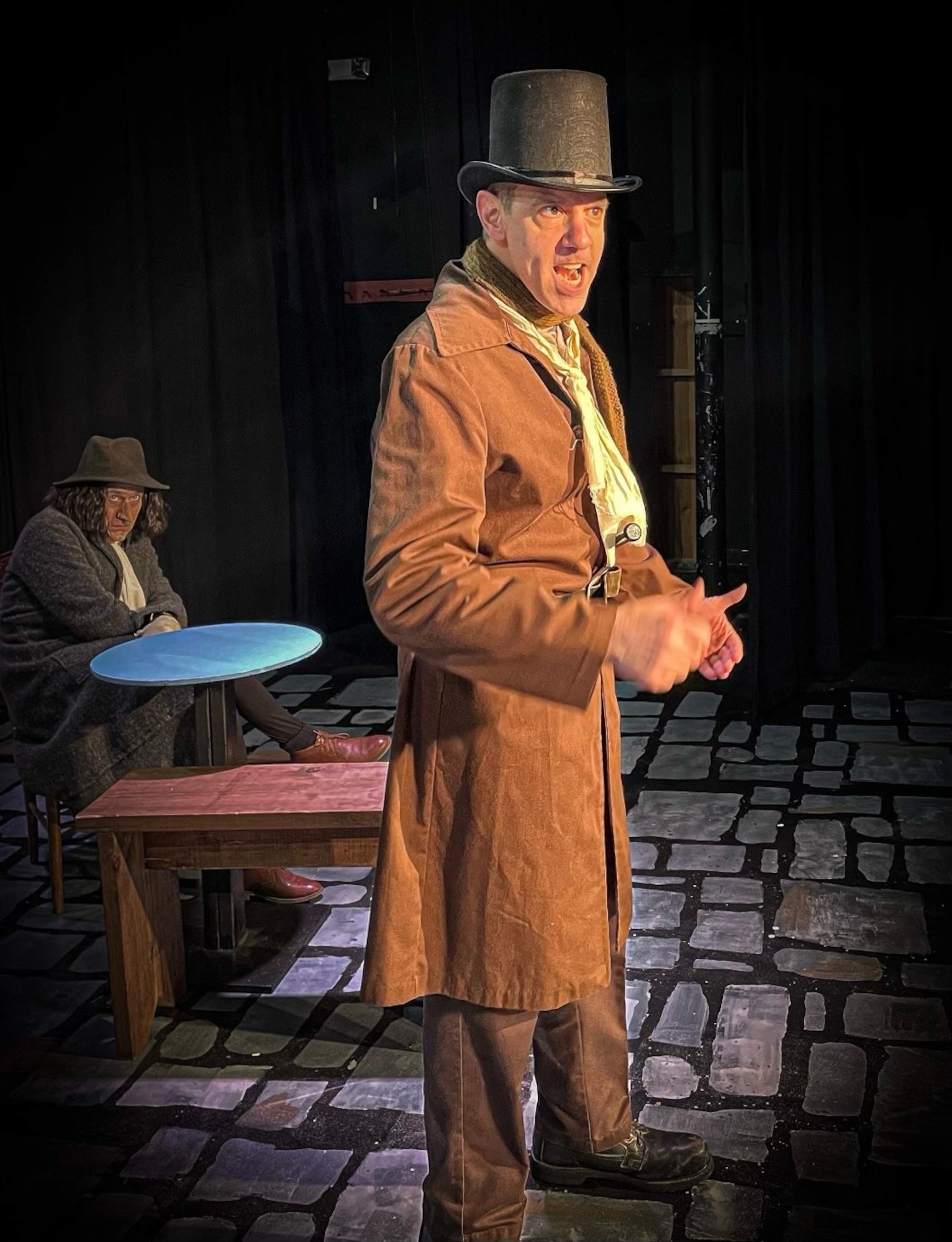 AEDC team member Frank Wonder stands and sings as his character Bill Sikes in the musical “Oliver!” during a rehearsal while AEDC team member J.D. Dill sits behind him looking on.