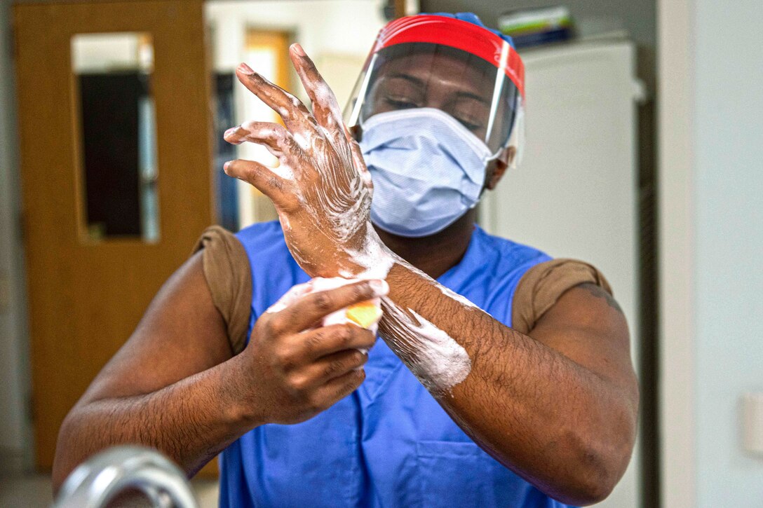 A student wearing protective gear washes their hands in a hospital.