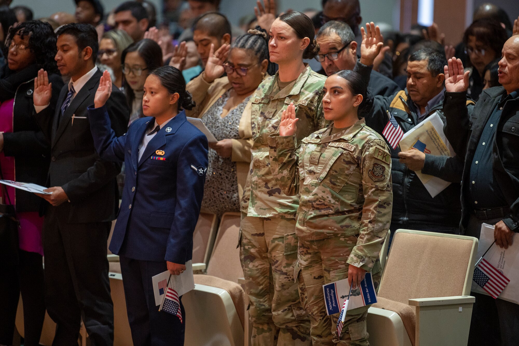 Airman Lissbeth Cardenas Idrovo, right, 22nd Contracting Squadron contracting specialist, performs the Oath of Allegiance at the Kansas Naturalization Ceremony Jan. 20, 2023, in Wichita, Kansas. She is accompanied by her supervisor, left, Staff Sgt. Cassandria McAfee. Airman Idrovo was one of two McConnell Airmen to become a U.S. Citizen that day, along with Airman Michelle Ashley, far left and in her blue service dress uniform. Airman Ashley is a full-time member of the Kansas Air National Guard's 184th Comptroller Flight at McConnell. During the ceremony 165 people from 46 countries became U.S. citizens. (U.S. Air Force photo by Airman 1st Class Brenden Beezley)
