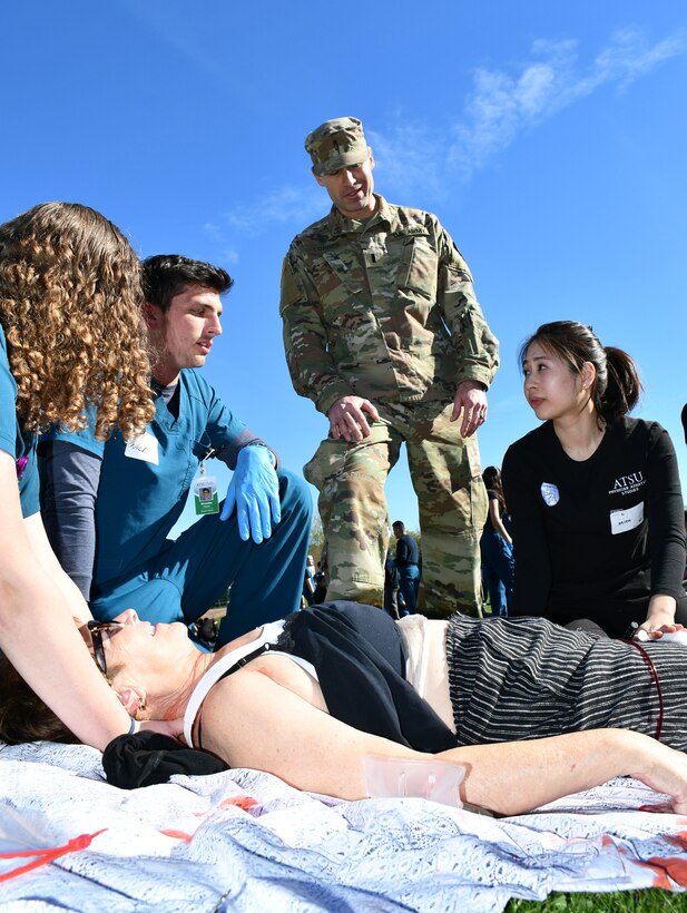 A student from the AT Still University School of Osteopathic Medicine cares for a simulated infant victim while his team briefs 1st Lt. Christina Kmotorka on the status of another patient. (US Army photo by Tim Dewar)