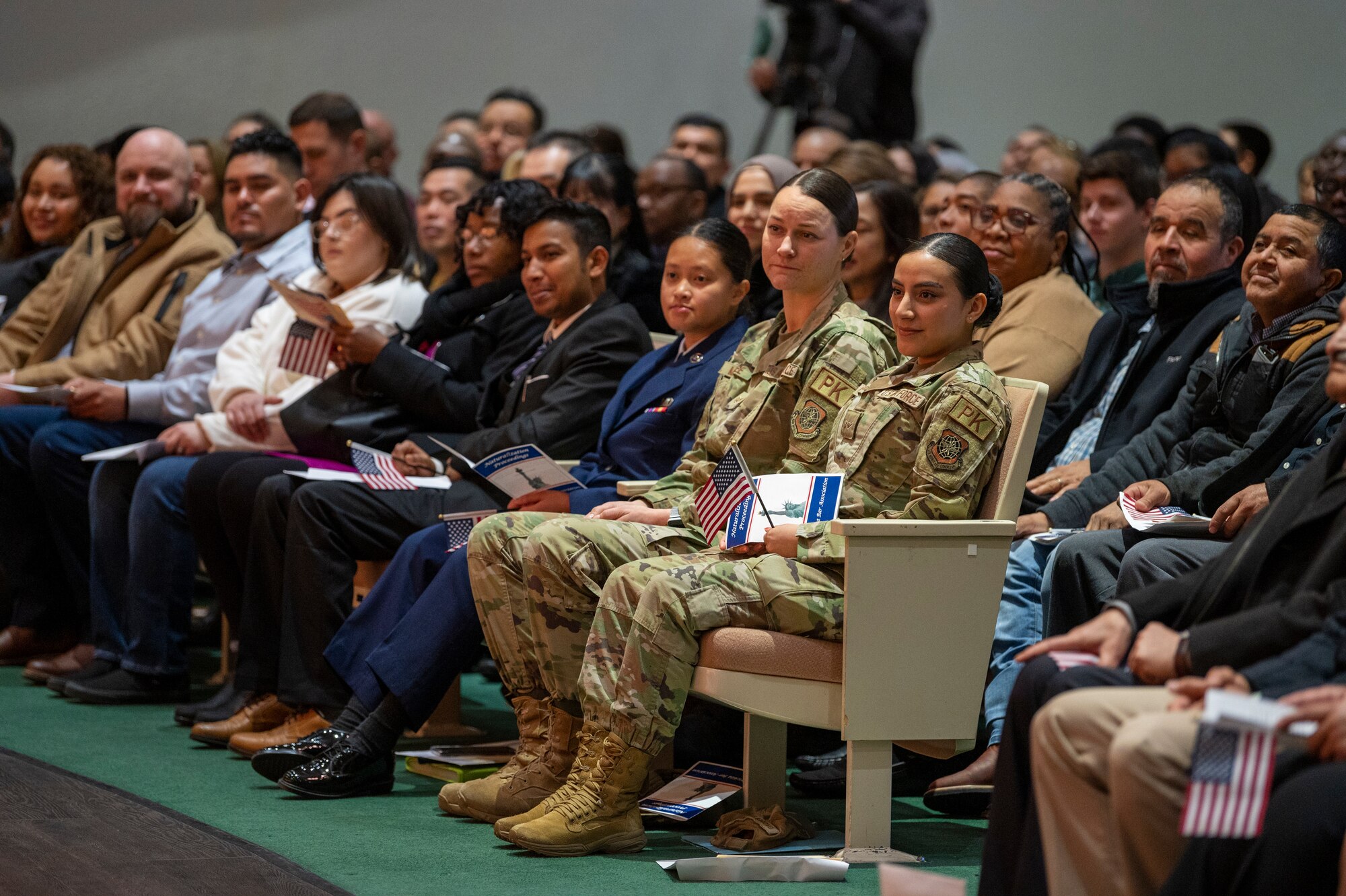 Airman Lissbeth Cardenas Idrovo, right, 22nd Contracting Squadron contracting specialist, attend a Kansas Naturalization Ceremony Jan. 20, 2023, in Wichita, Kansas. She is accompanied by her supervisor, left, Staff Sgt. Cassandria McAfee. Airman Idrovo was one of two McConnell Airmen to become a U.S. Citizen that day, along with Airman Michelle Ashley, far left and in her blue service dress uniform. Airman Ashley is a full-time member of the Kansas Air National Guard's 184th Comptroller Flight at McConnell. During the ceremony 165 people from 46 countries became U.S. citizens. (U.S. Air Force photo by Airman 1st Class Brenden Beezley)