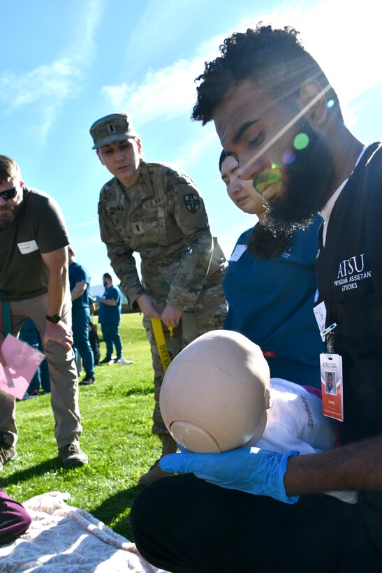 A student from the AT Still University School of Osteopathic Medicine cares for a simulated infant victim while his team briefs 1st Lt. Christina Kmotorka on the status of another patient. (US Army photo by Tim Dewar)