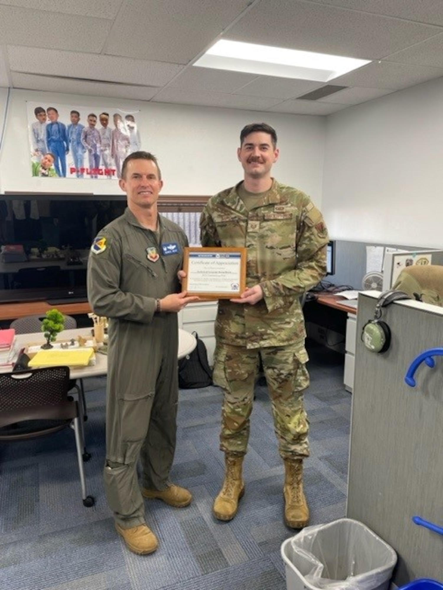 Two people hold a recognition award.