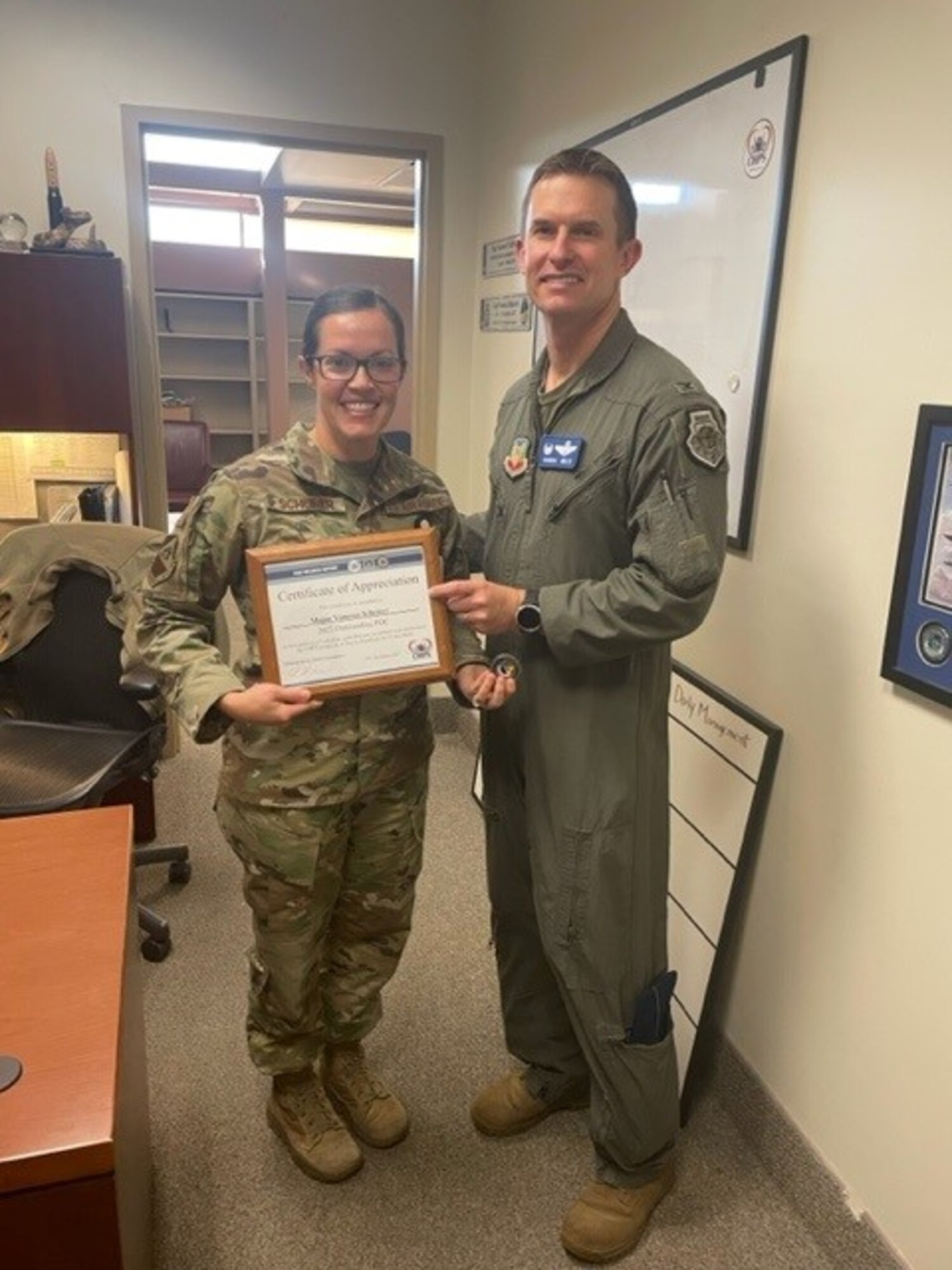 Two people hold a recognition award.