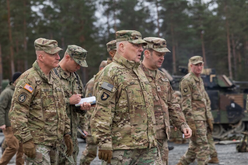 Uniformed personnel walk together outdoors.