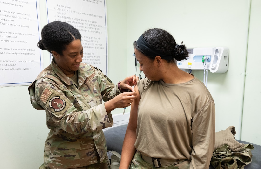 Senior Airman Lydia Payne (left), 8th Healthcare Operations Squadron allergy and immunology technician, gives a bandage to Staff Sgt. Sadie Colbert, 8th Fighter Wing public affairs technician, at Kunsan Air Base, Republic of Korea, Jan. 18, 2023. The immunization services were one of the many services inspected during the 8th Medical Group’s The Joint Commission accreditation process, helping the group achieve a successful rating. (Courtesy Photo)