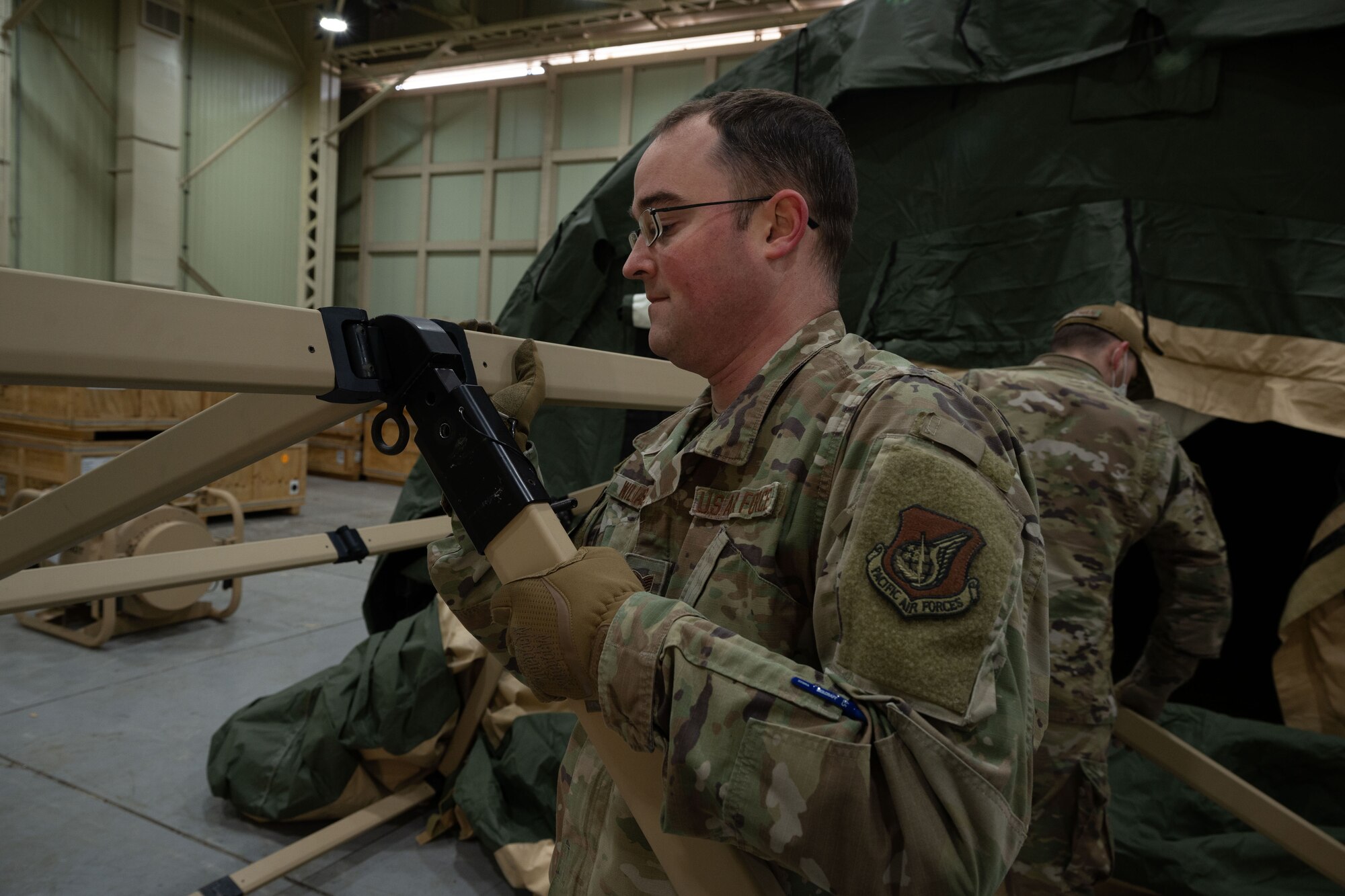 Tech. Sgt. Jordan Williams, 354th Medical Group NCO in charge of medical materiel from Eielson Air Force Base, Alaska, assembles the frame of the multi-functional entrance at Kunsan Air Base, Republic of Korea, Jan. 20, 2023. A tent kit 2 chemical protection system can protect up to 20 personnel from chemical, biological, radiological, and nuclear contamination for up to 48 hours. (U.S. Air Force photo by Senior Airman Akeem K. Campbell)