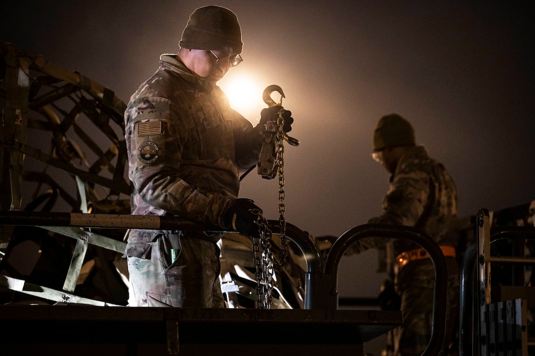 Two airmen load cargo at night.