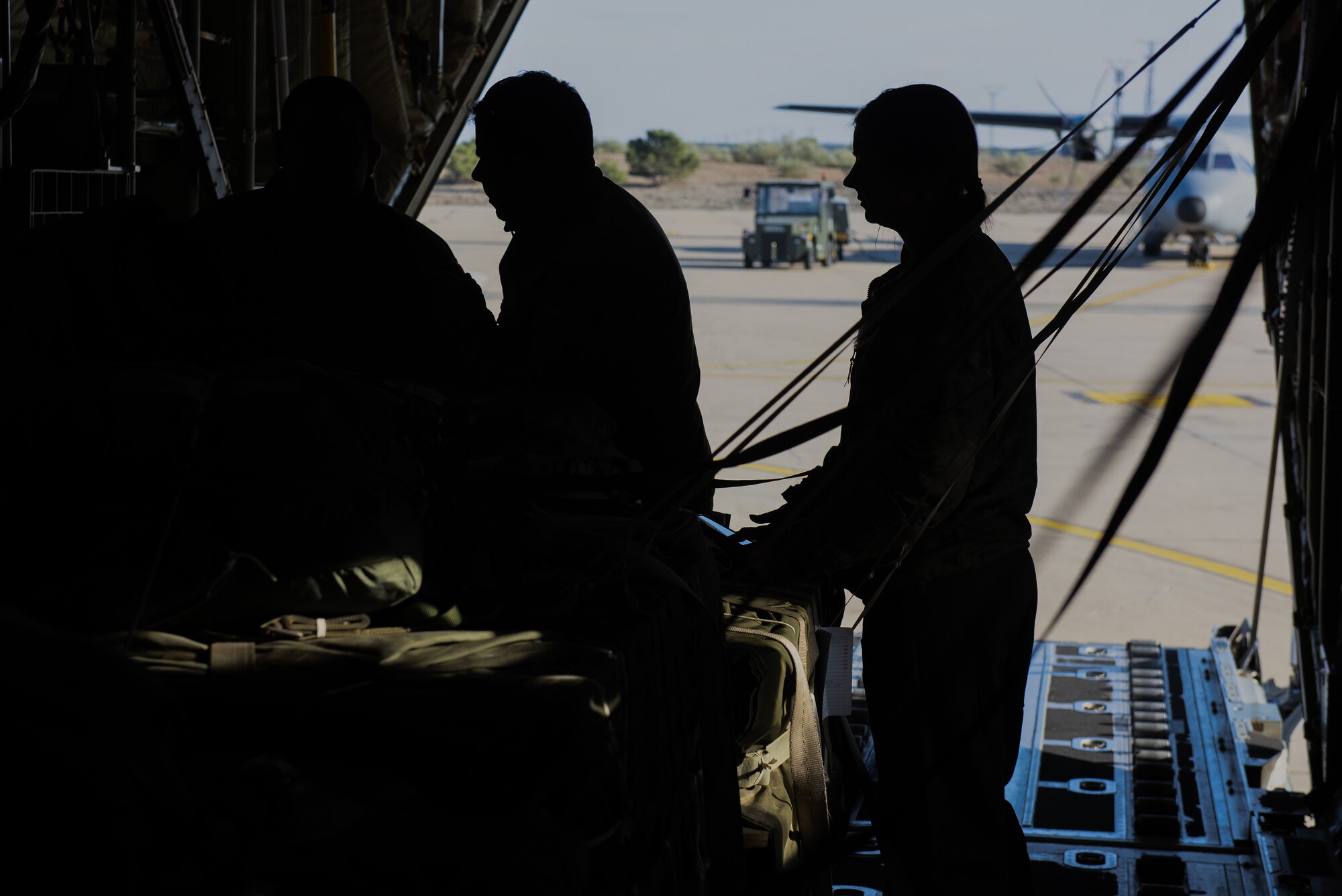 3 silhouettes of people secure cargo in a plane