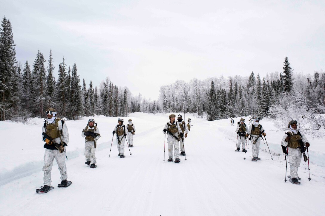 Airmen walk through a snow-covered road.