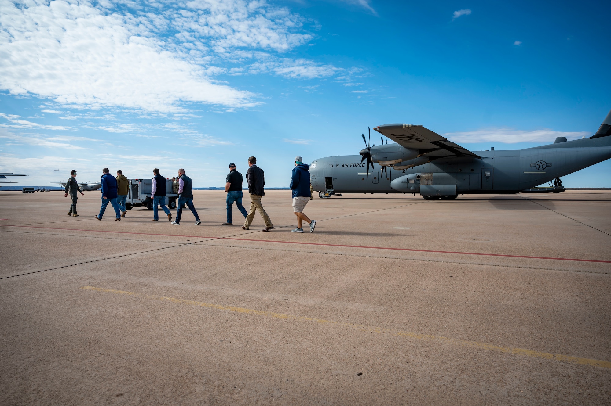 A group of honorary commander inductees walk towards a C-130J Super Hercules during an honorary commander induction tour incentive flight at Dyess Air Force Base, Texas, Jan. 20, 2023. The Honorary Commanders Program is an executive-level program intended to educate community members who have limited knowledge of the Air Force and Dyess to foster public support for the base and its Airmen and families. (U.S. Air Force photo by Senior Airman Leon Redfern)