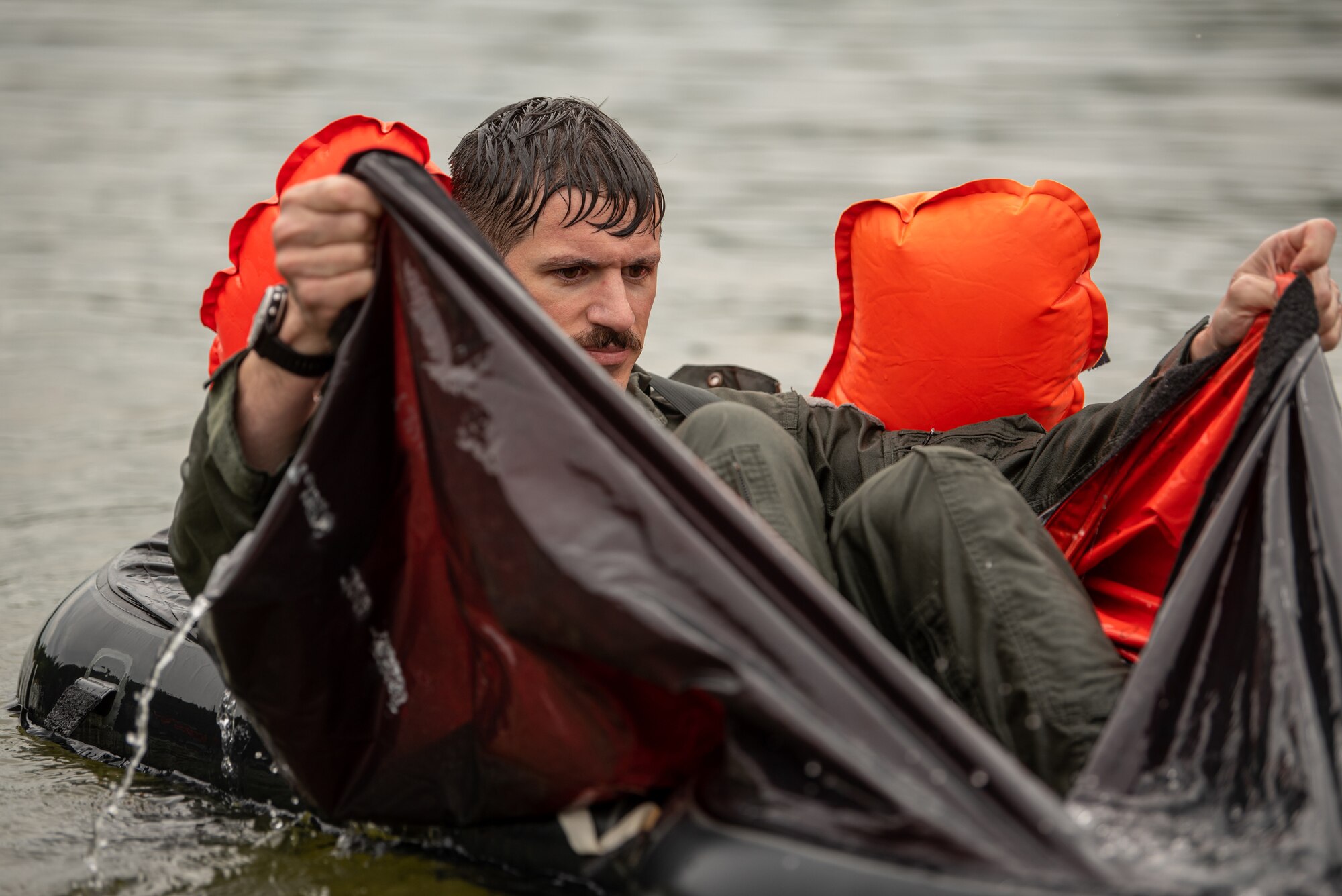 Lt. Col. Matt Hamblen, a pilot for the Kentucky Air National Guard’s 165th Airlift Squadron, bails water out of a LRU-16/P life raft with the spray shield during water survival training at Taylorsville Lake in Spencer County, Ky., Sept. 10, 2022. The annual training refreshes aircrew members on skills learned during U.S. Air Force Survival School. (U.S. Air National Guard photo by Tech. Sgt. Joshua Horton)