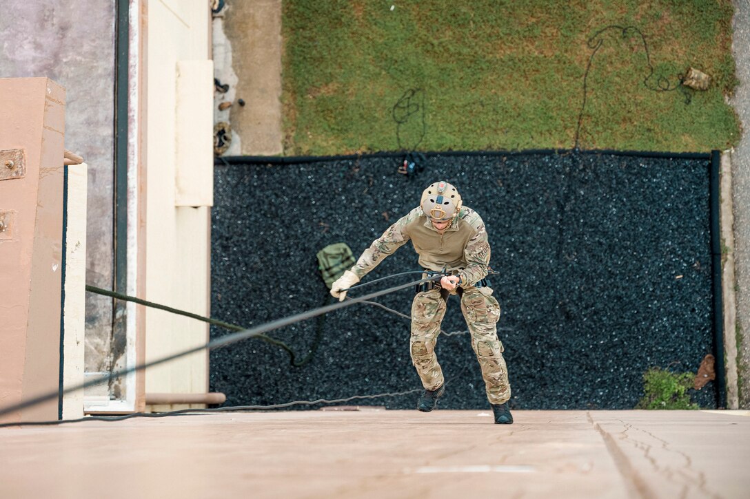A sailor rappels down a tower as seen from above.