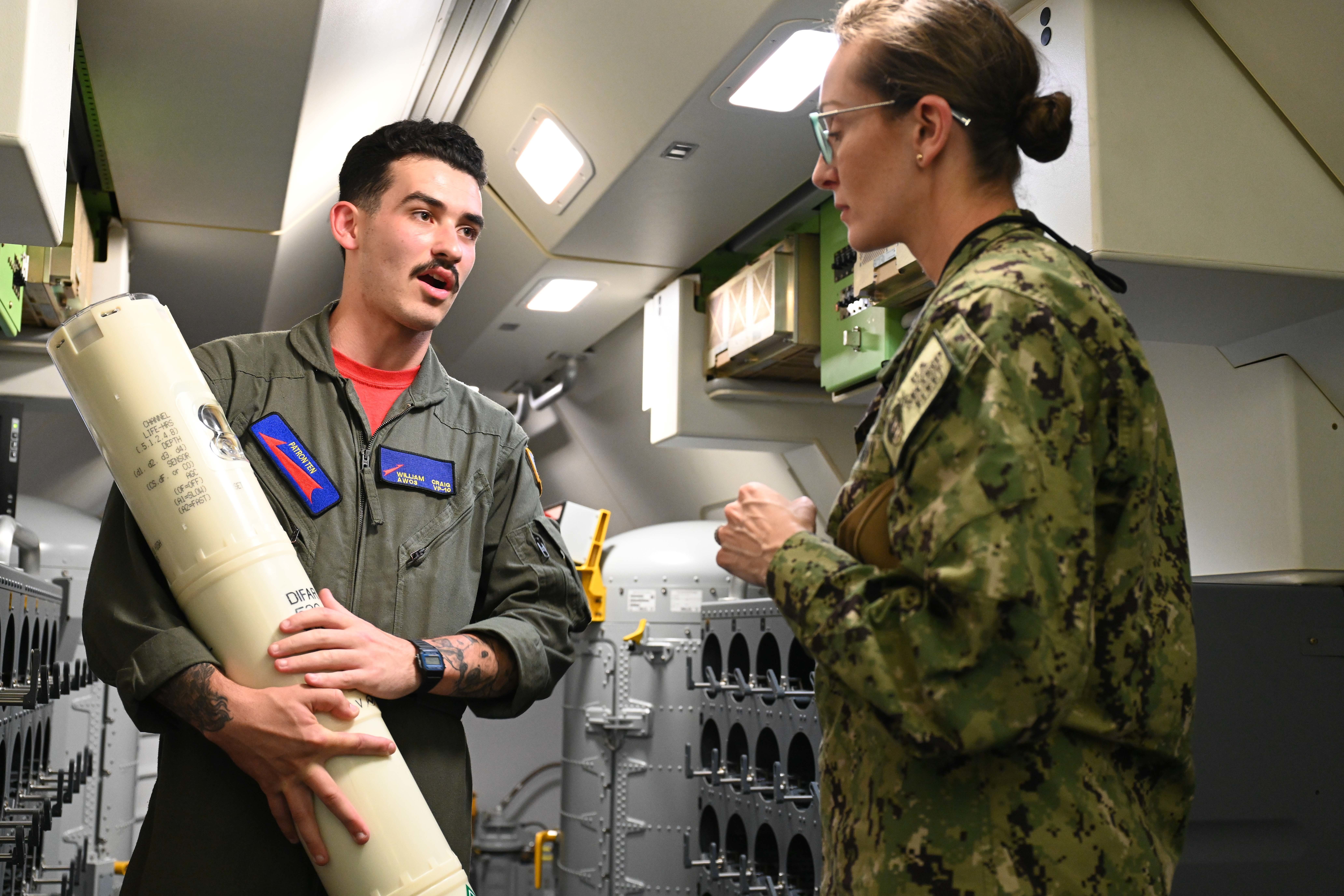 NORFOLK, Va. (April 26, 2022) – Naval Air Crewman 3rd Class William Craig, left, shows Lt. Cmdr. Alaina Tibaneli a sonar buoy aboard a P-8A Poseidon maritime patrol and reconnaissance aircraft during a Junior Officer Undersea Warfare Symposium and Training (JOUST) platform tour onboard Naval Station Norfolk. JOUST is an annual symposium led by junior officers designed to address challenges to future undersea warfare (USW) operations and leverage and maximize strengths in the USW community.  (U.S. Navy photo by Mass Communication Specialist 1st Class Justin Yarborough/Released)